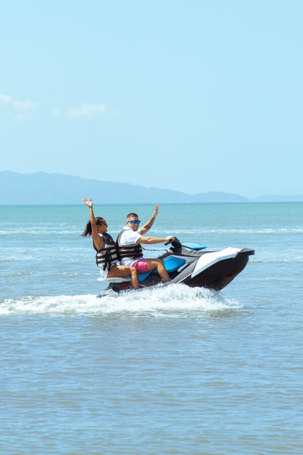 A man and woman riding on the back of a jet ski.