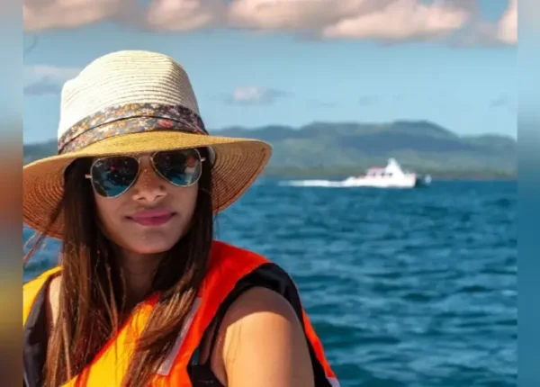 A woman in an orange life vest and hat on the water.