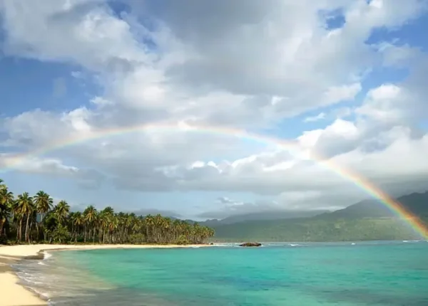 A rainbow over the ocean and a beach.