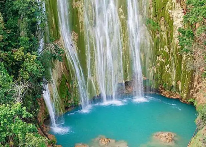 A waterfall with green trees and blue water.