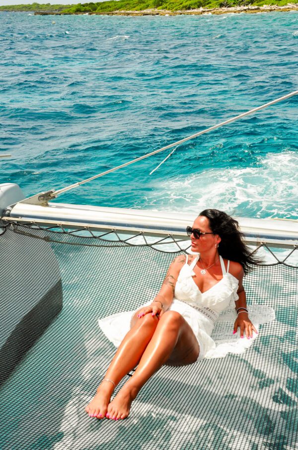 A woman in white dress sitting on the back of a boat.