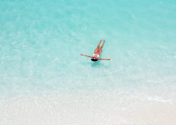 A person floating in the water on their stomach.